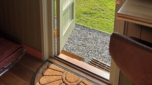 An open door leading to a grassy yard with a wooden bench and a doormat. - Shepherd's Hut with mountain and valley views on the Mach Loop flightpath (Dolgellau)