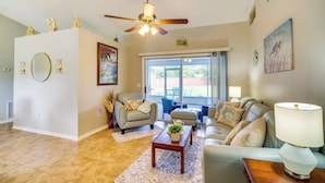 A living room with a ceiling fan, a sofa, a coffee table, and a lamp. - 3-bedroom house in peaceful Melbourne with cool AC (Melbourne)