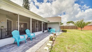 A covered patio with outdoor seating, a lawn, and a wooden fence. - 3-bedroom house in peaceful Melbourne with cool AC (Melbourne)