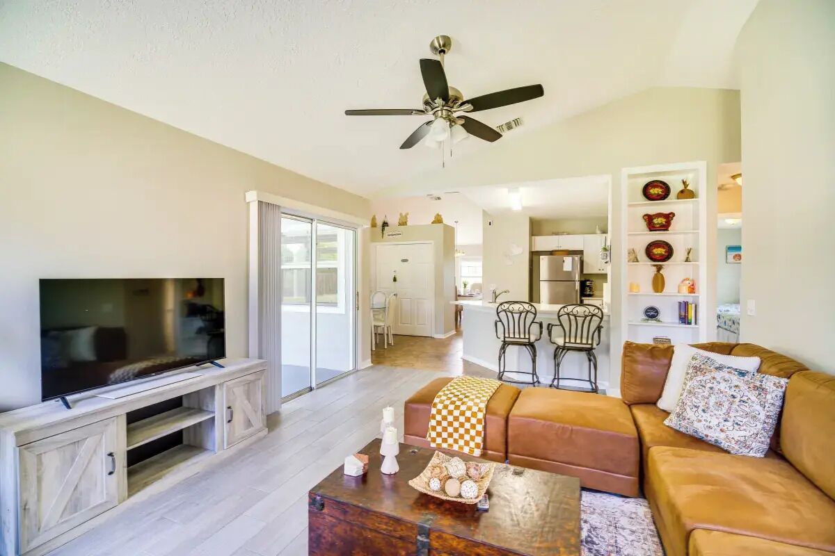 A living room with a TV, sofa, coffee table, and a ceiling fan.