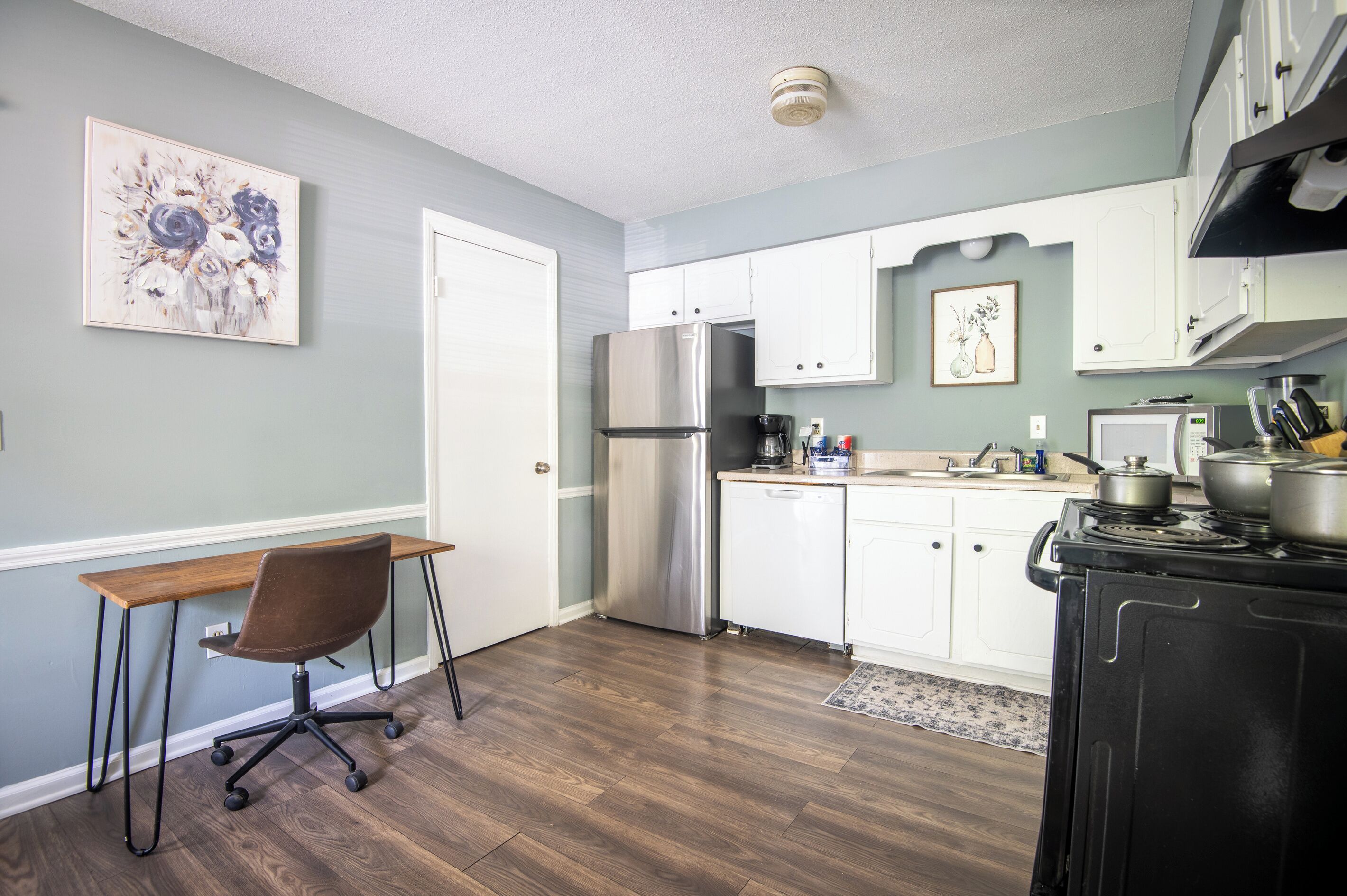 A kitchen with a refrigerator, stove, and cabinets.