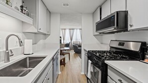 Une cuisine compacte équipée d’une cuisinière, d’un évier et d’un four à micro-ondes. Un coin repas avec une table et des chaises est également disponible.