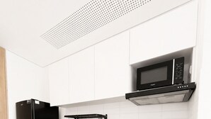 Une cuisine moderne avec un réfrigérateur noir, des armoires blanches, un four à micro-ondes et un évier en acier inoxydable.