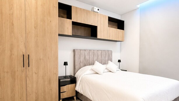 Une chambre moderne avec un grand lit, une armoire en bois, des étagères intégrées et une table de chevet.