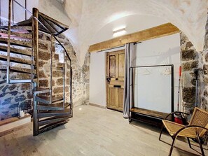 Huone, jossa on kierreportaat, puuovi, valkotaulu ja punottu tuoli.