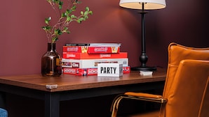Une table avec des jeux de société, une lampe et une chaise.