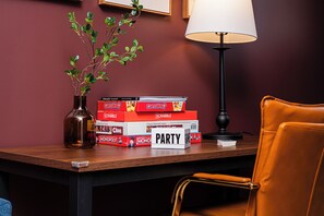 Ein Tisch mit Gesellschaftsspielen, einer Lampe und einem Stuhl.