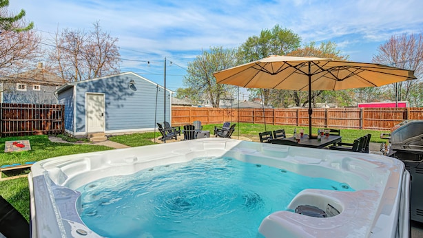 Un jardin avec un jacuzzi, du mobilier d’extérieur et une clôture en bois.