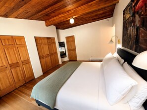 Une chambre avec un grand lit, une armoire en bois et un tableau accroché au mur.