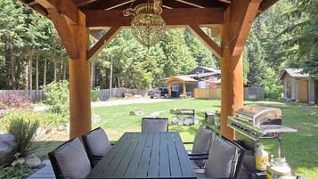 An outdoor wooden deck with a table and chairs, a grill, and a pergola structure.