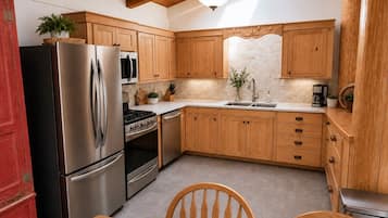 Une cuisine avec des meubles de rangement en bois, un réfrigérateur en acier inoxydable, une cuisinière et un évier.
