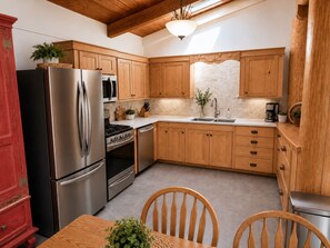 A kitchen with wooden cabinets, a stainless steel refrigerator, a stove, and a sink.