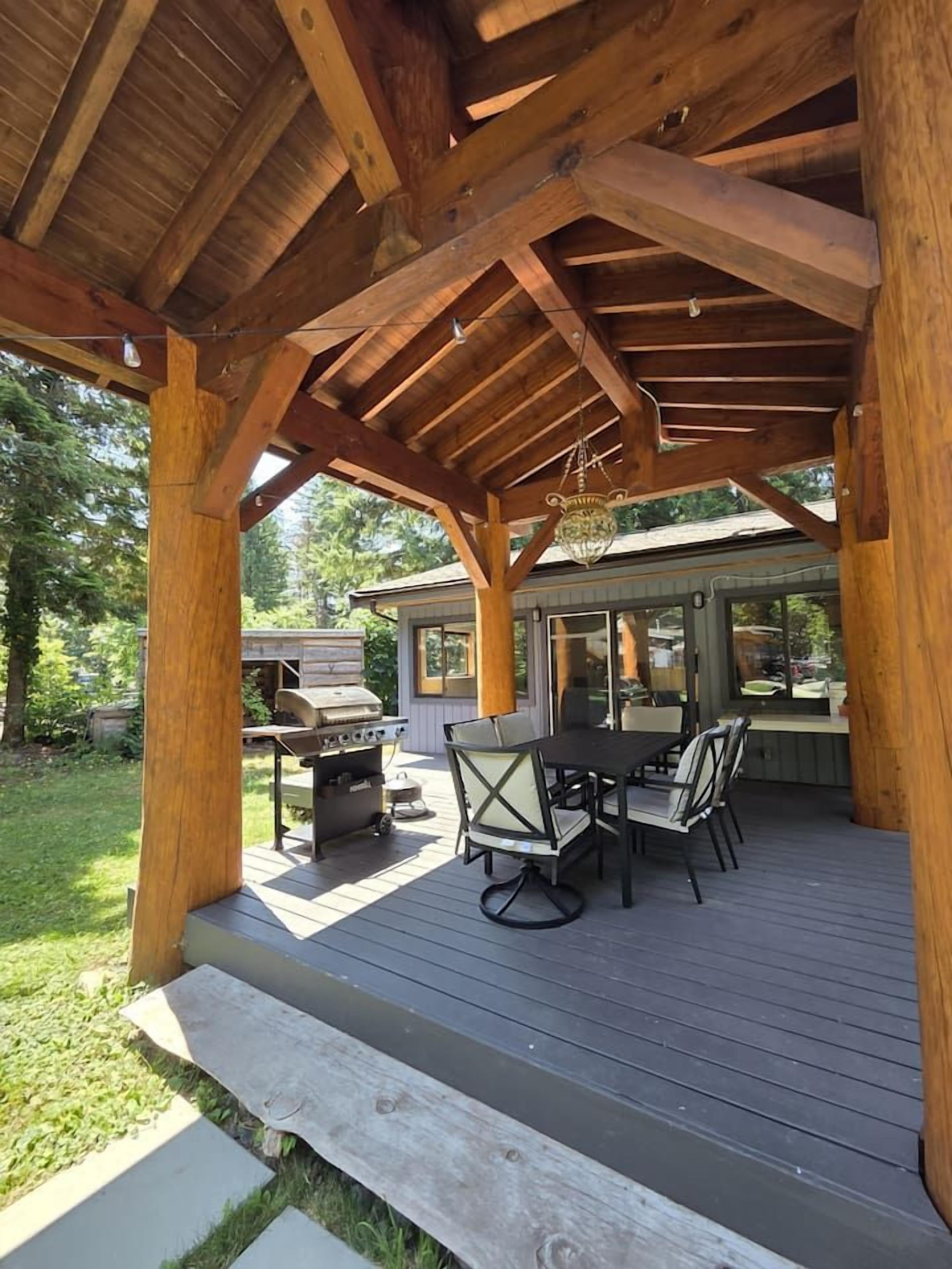 A covered outdoor patio with a grill, table, and chairs.