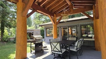 Un patio extérieur abrité, équipé d’un barbecue, d’une table et de chaises.