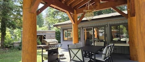 A covered outdoor patio with a grill, table, and chairs.