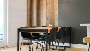 A dining area with a wooden table, black chairs, and a vertical wooden slat wall. - Coastal Retreat / Near 30A / Pool / 4BR / Sleeps 10 (Santa Rosa Beach)