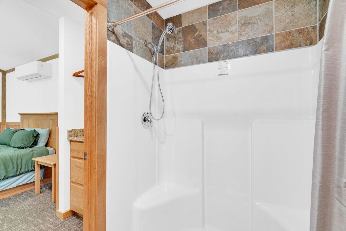 Une salle de bain avec douche, un lit en bois et une petite table.