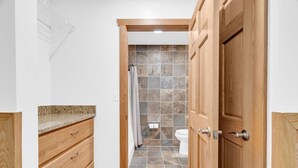 A bathroom with a shower, toilet, and wooden cabinetry.