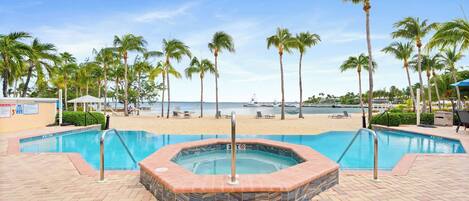 Una piscina con hidromasaje, palmeras y vista al mar.