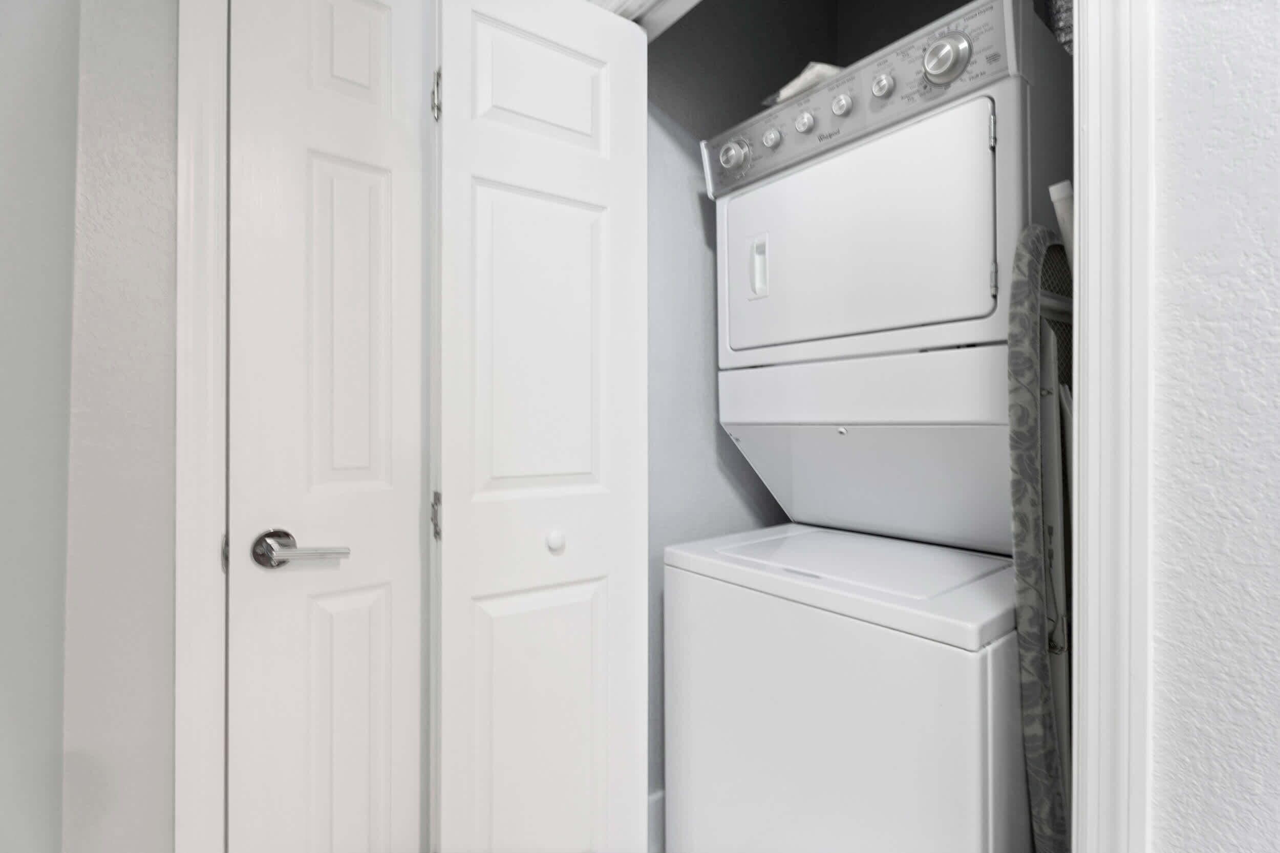 A laundry room with a washer and dryer, a white door, and a white wall.