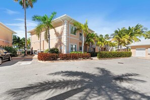 A multi-story building with a flat roof, surrounded by palm trees and a parking lot.