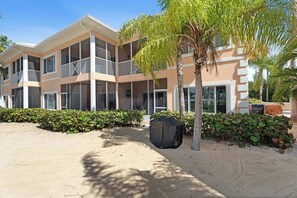A multi-story hotel with balconies, a covered outdoor seating area, and a sandy courtyard. - Kai-Tastic 15B - 2BR Kaibo Condo with Pool and Beach (Rum Point)