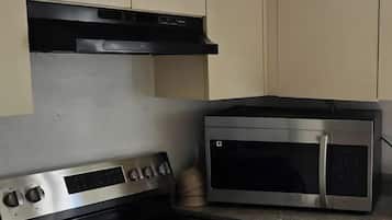 A kitchen with a stove, microwave, and cabinets.