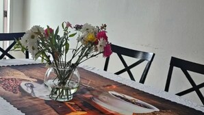 Et spisebord med hvid dug, en vase med blomster og en dekorativ bordløber.