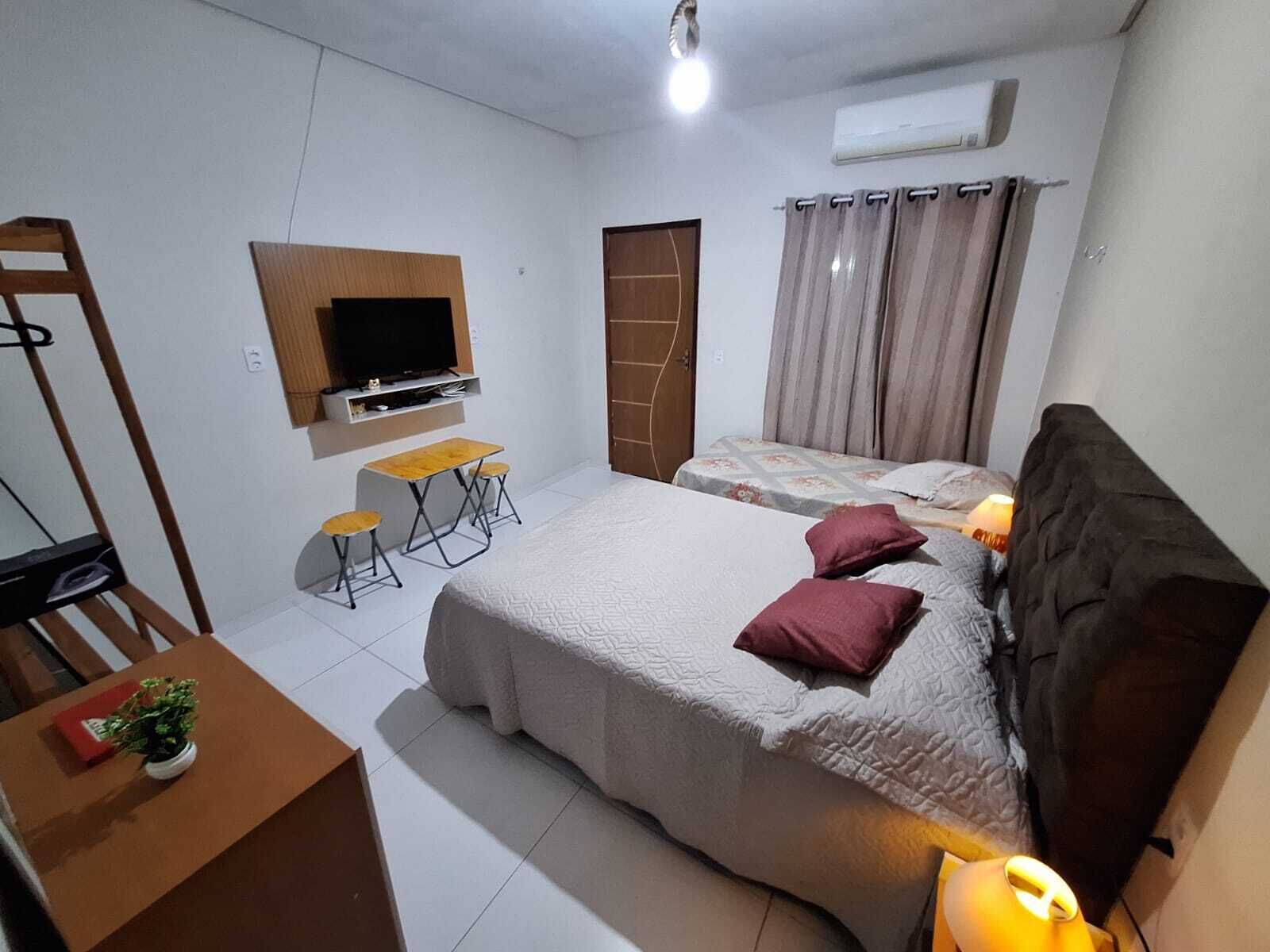 Une chambre à coucher avec un lit, un bureau, une chaise, une télévision et une fenêtre avec des rideaux.