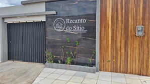 A modern building facade with a black wall featuring a logo and text 'Recanto do Sítio' indicating a property or event space. - Chácara Recanto do Sítio (Barbalha)