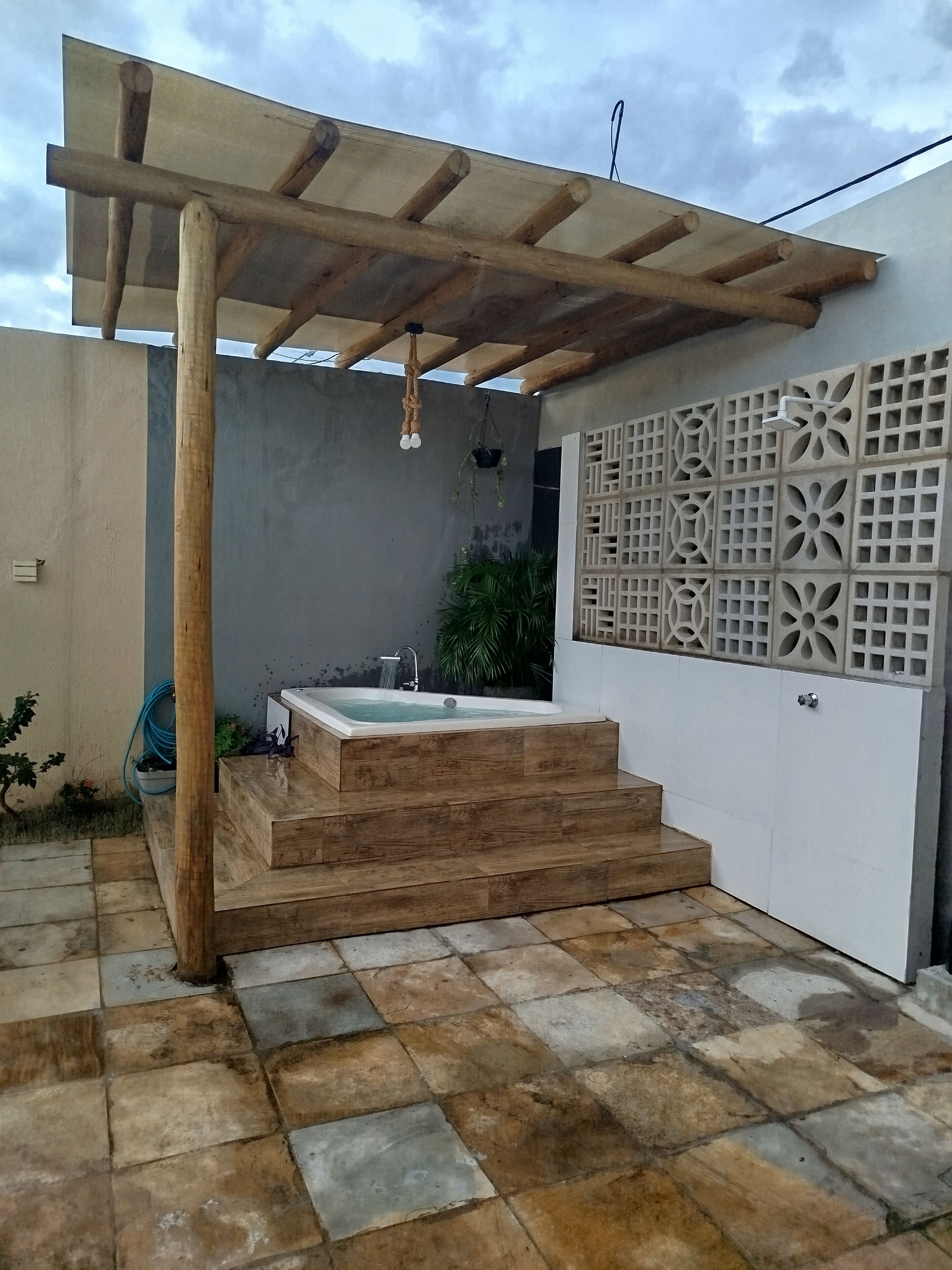 Un área de spa con una pérgola de madera, un jacuzzi y una pared decorativa.