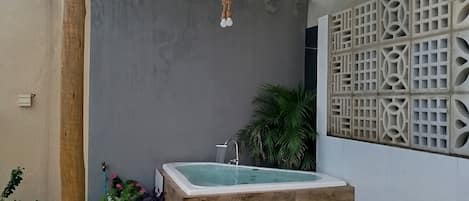 Un espace de bien-être comprenant un jacuzzi, des marches en bois, une pergola et un mur décoratif.