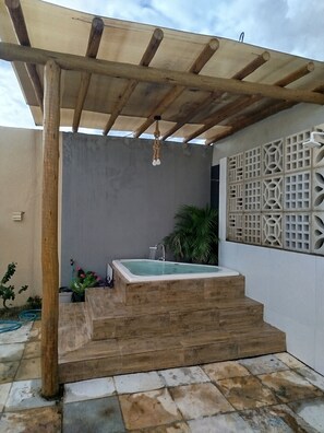 A spa area with a hot tub, wooden steps, a pergola, and a decorative wall. - Chácara Recanto do Sítio (Barbalha)