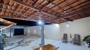 Un espacio interior con techo de madera, un banco de madera y suelo de baldosas.