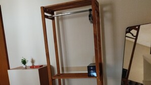 A room with a wooden shelf unit, a mirror, and a small plant on a cabinet. - Chácara Recanto do Sítio (Barbalha)