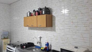 Una cocina con estufa a gas, microondas, lavamanos y alacenas.