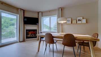 A dining area with a fireplace, large windows, and a view of greenery.