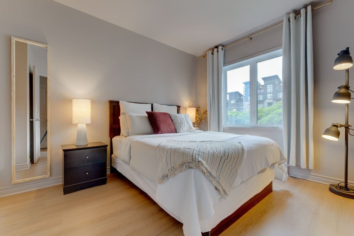 A bedroom with a bed, bedside table, lamp, and a window with curtains.