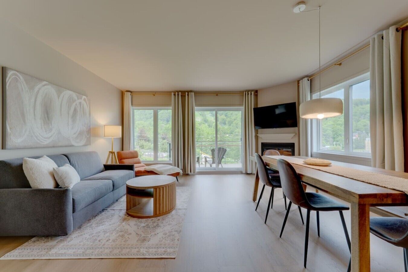 A modern living room with a sofa, coffee table, dining table, chairs, a fireplace, and a TV.