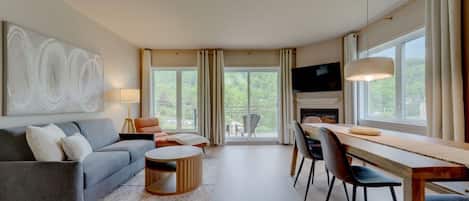 Una sala de estar moderna con sofá, mesa de centro, mesa de comedor, sillas, chimenea y televisor.
