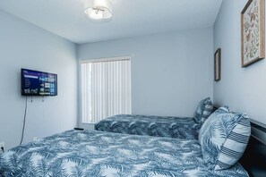 A bedroom with a bed, a TV mounted on the wall, and a window with blinds. - 4BR Kissimmee Home Near Disney With Pool (Kissimmee)