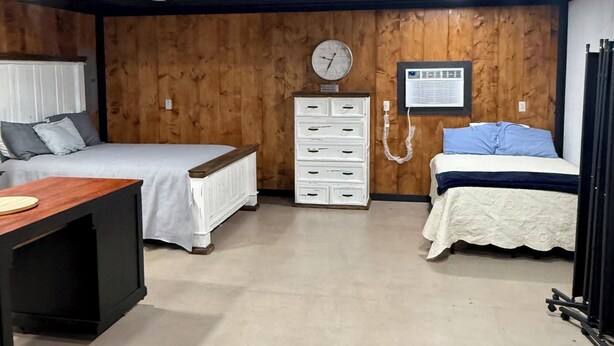 A bedroom with two beds, a wooden wall, a clock, a dresser, and a desk. - Lake house minutes from the boat dock w/attached garage for boats or vehicles (Foss)