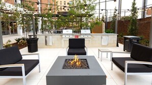 An outdoor patio with a fire pit, seating, and a grill. - The Foundry Studio | Downtown Retreat St3 (Birmingham)