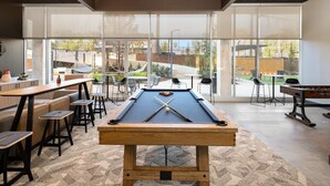 A pool table in a room with large windows, a bar area, and outdoor seating. - The Foundry Studio | Downtown Retreat St3 (Birmingham)