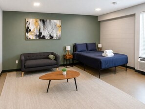 A room with a sofa, a bed, a coffee table, and a painting on the wall. - The Foundry Studio | Downtown Retreat St4 (Birmingham)