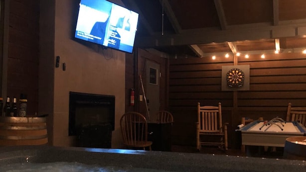 Ett rum med ett bubbelbad, en tv som är monterad på väggen och en darttavla.