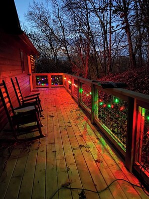 Eine Holzterrasse mit Geländer, umgeben von Bäumen.