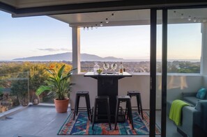 Een balkon met een tafel, stoelen en een bloempot.