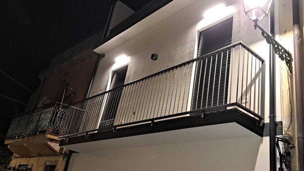 A building with a balcony, a window, and a light fixture. - 15 minutes from Taormina, 20 meters from the sea: La Casa di Lucio - I Pupi Apartment (Nizza di Sicilia)