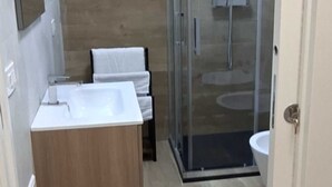 A bathroom with a wooden vanity, a glass shower enclosure, and a white sink. - 15 minutes from Taormina, 20 meters from the sea: La Casa di Lucio - I Pupi Apartment (Nizza di Sicilia)